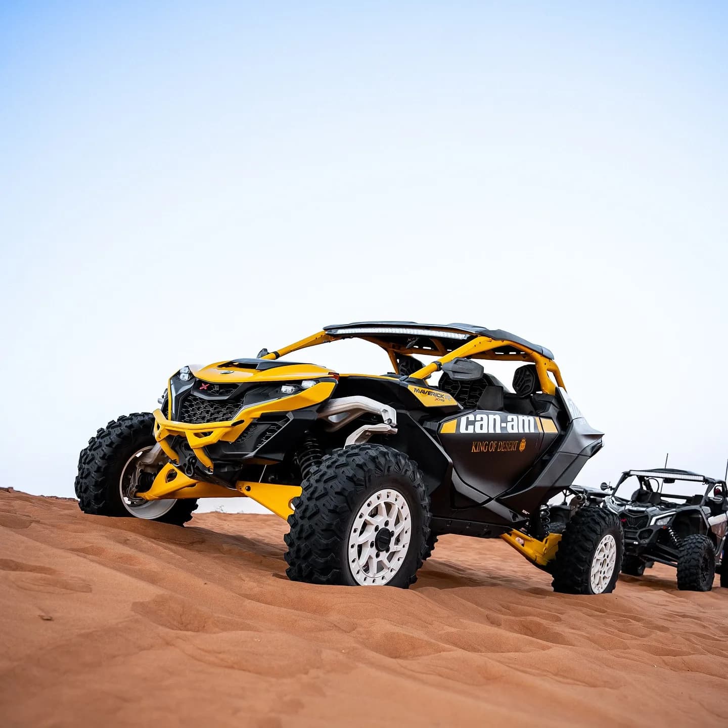 Yellow and black Can-Am Maverick R XRS on top of a Dubai dune